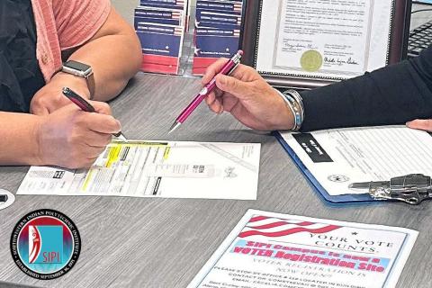 Photo of a citizen signing a voter registration form.