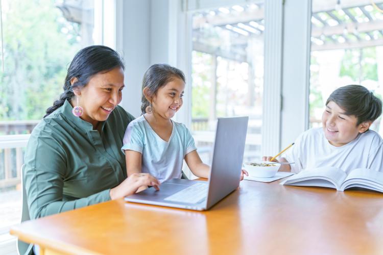 woman and children at table doing homework
