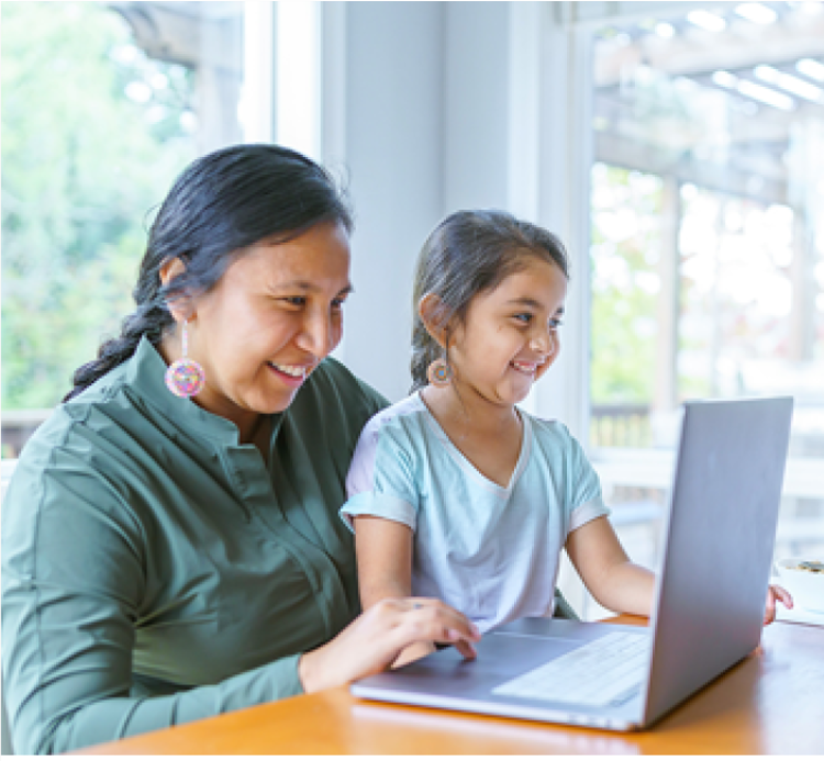adult and child smiling and looking at laptop together