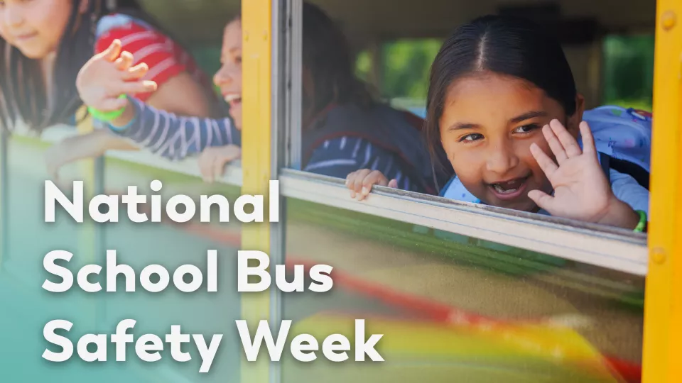 A child waving inside a school bus.