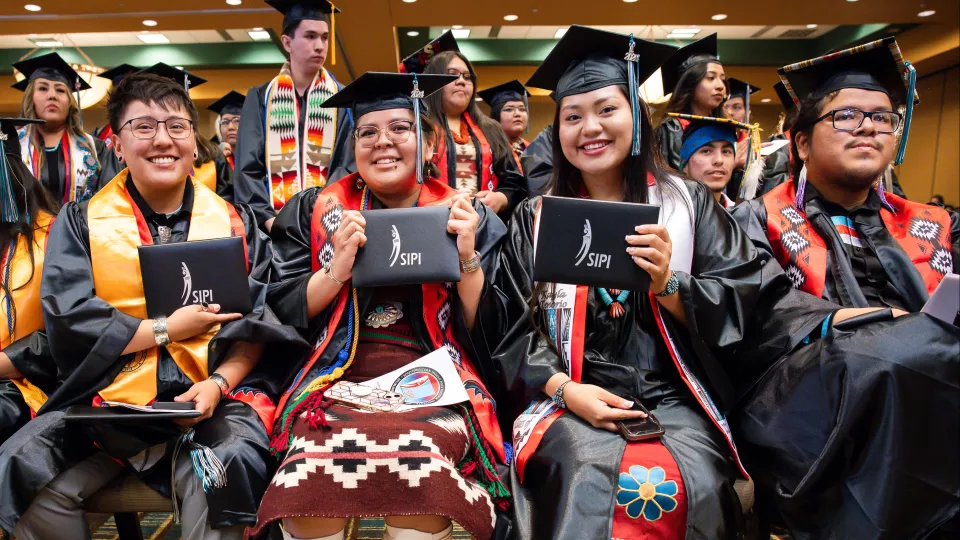 SIPI Students show off their diplomas on graduation day in 2024