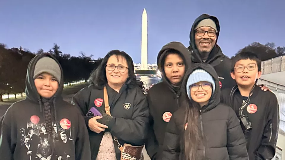 A group of four children and two adults stand in front of the Washington Monument in Washington DC.